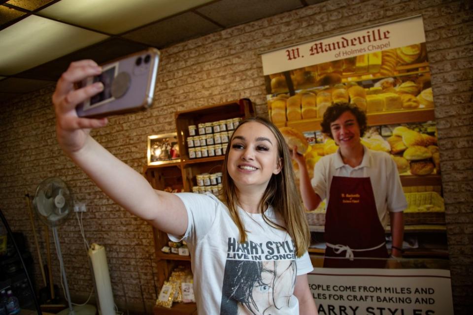 Izzy Hawksworth poses for a selfie with a picture of a young Styles at the bakery he used to work at, Mandeville Bakery, in Holmes Chapel. William Lailey SWNS