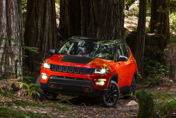 A red 2018 Jeep Compass Trailhawk, a compact SUV, in a forest.