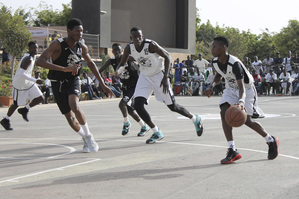 FILE - Guard Moustapha Mboup, right, dribbles the ball as teammate Ibou Badji, center, and Efe Abogidi follow the action, at the SEED Project Hoop Forum in Dakar, Senegal, on May 7, 2017. Several prospects from the NBA Academy in Africa are playing in the new season of the Basketball Africa League. Now in its third season, the league was created by the NBA in partnership with FIBA to help grow the sport in Africa. (AP Photo/Kenneth Maguire, File)