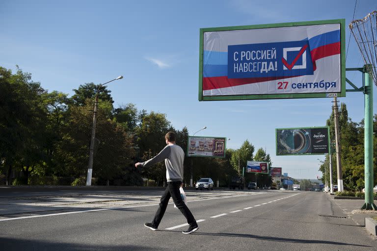 Un hombre cruza una calle con un cartel que dice 