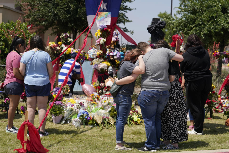 Abbi Boyd, center left, hugs Dakota Britvich, gray shirt, and Jennifer Seeley, front right, as they stand at a makeshift memorial by the mall where several people were killed in Saturday's mass shooting, Monday, May 8, 2023, in Allen, Texas. (AP Photo/Tony Gutierrez)