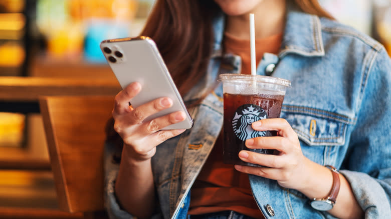 Person holding phone and iced coffee