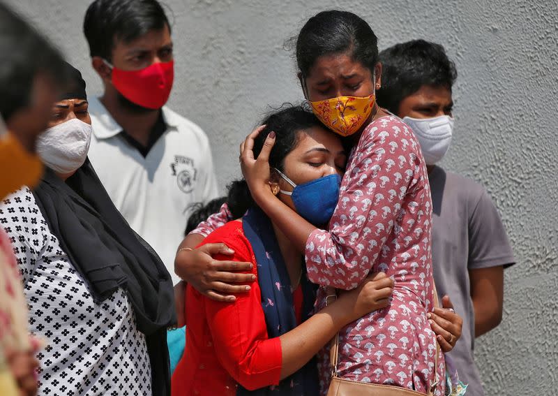 A woman is consoled after her husband died due to the coronavirus disease (COVID-19) outside a mortuary of a COVID-19 hospital in Ahmedabad