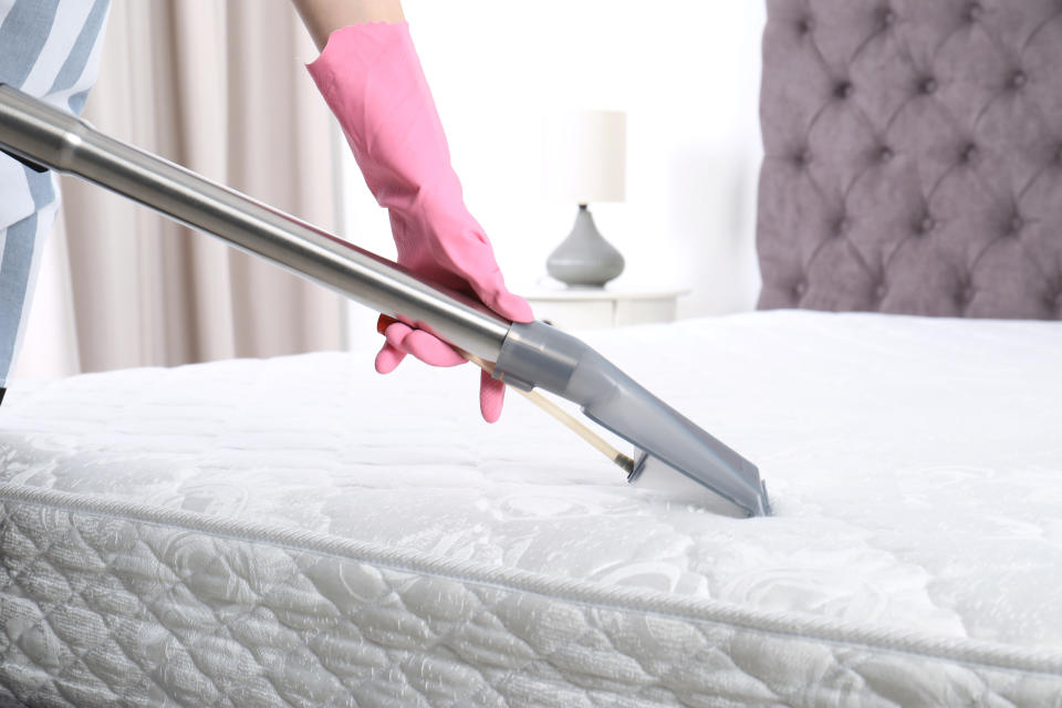 Woman disinfecting mattress with vacuum cleaner, closeup. Space for text