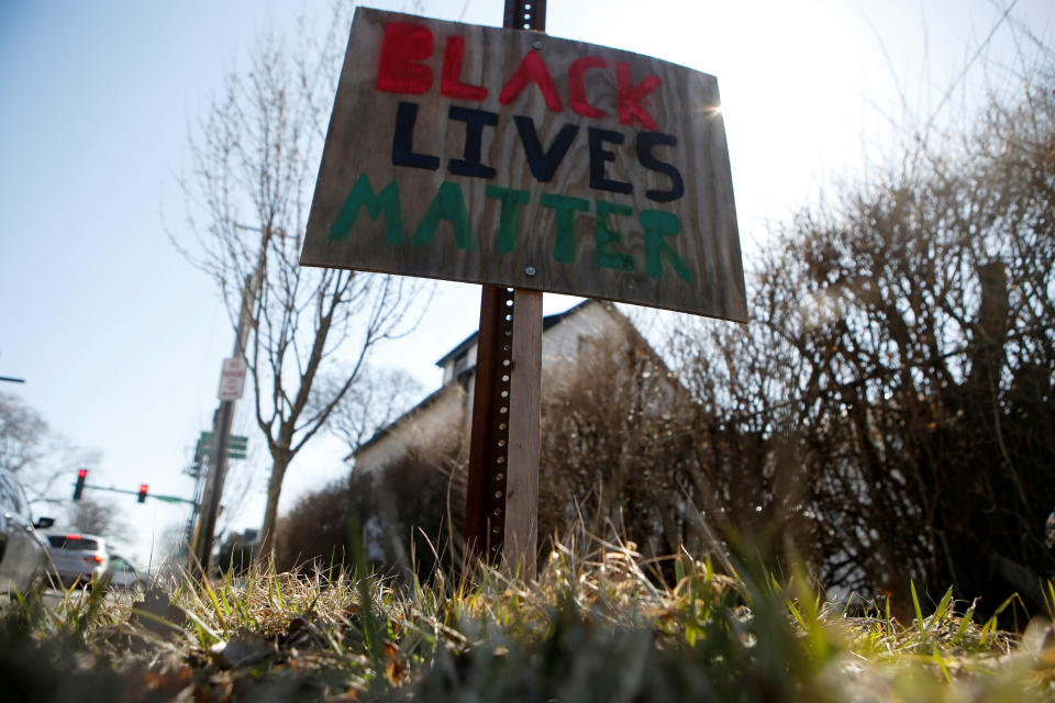 A hand-lettered Black Lives Matter sign on a piece of plywood posted close to an intersection.