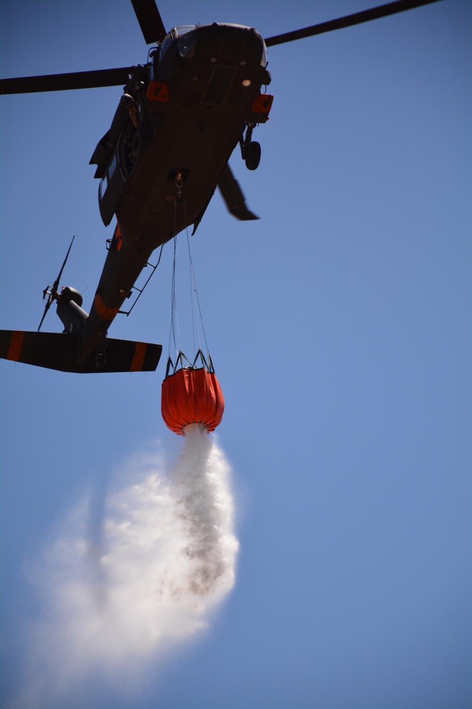In this photo provided by the New Mexico National Guard, New Mexico National Guard Aviation soldiers execute water drops as part of firefighting efforts, dropping thousands of gallons of water from a UH-60 Black Hawks with Bambi buckets on the Calf Canyon/Hermits Peak fire in northern New Mexico Sunday, May, 1, 2022. Thousands of firefighters are battling destructive wildfires in the Southwest as more residents are preparing to evacuate. (New Mexico National Guard via AP)