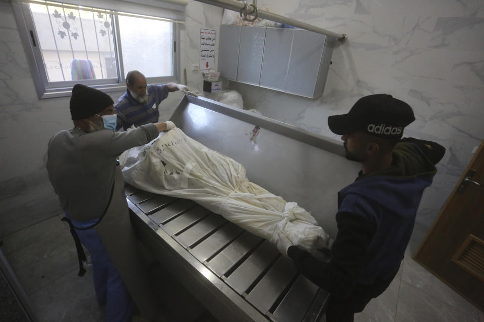 Morgue workers prepare bodies of Palestinians killed in the Israeli bombardment of the Gaza Strip for a funeral in Khan Younis, Tuesday, Dec. 26, 2023. (AP Photo/Hatem Ali)