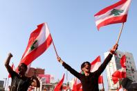 Demonstrators carry national flags and gesture during an anti-government protest in Tripoli