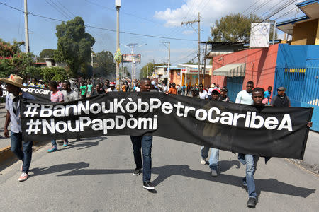 Demonstrators hold a banner during a protest against former government officials accused of misusing Petrocaribe funds and the country's inflation rate in Port-au-Prince, Haiti February 7, 2019. REUTERS/Jeanty Junior Augustin