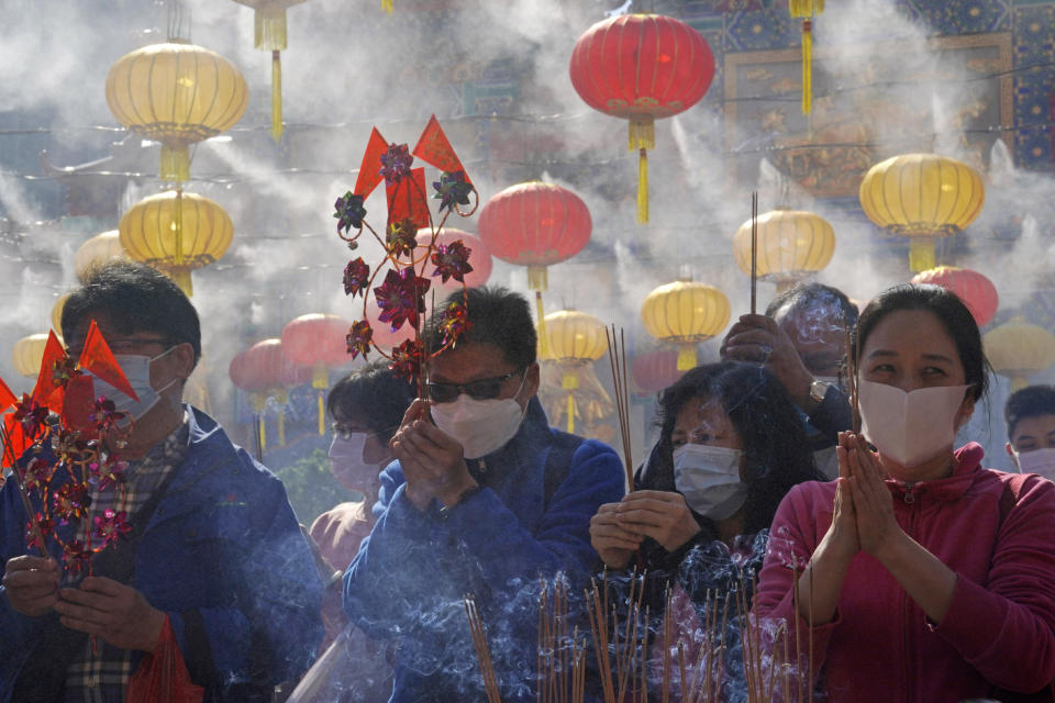 Worshippers wearing face masks to protect against the spread of the coronavirus, burn joss sticks as they pray at the Wong Tai Sin Temple, in Hong Kong, Friday, Feb. 12, 2021, to celebrate the Lunar New Year which marks the Year of the Ox in the Chinese zodiac. (AP Photo/Kin Cheung)