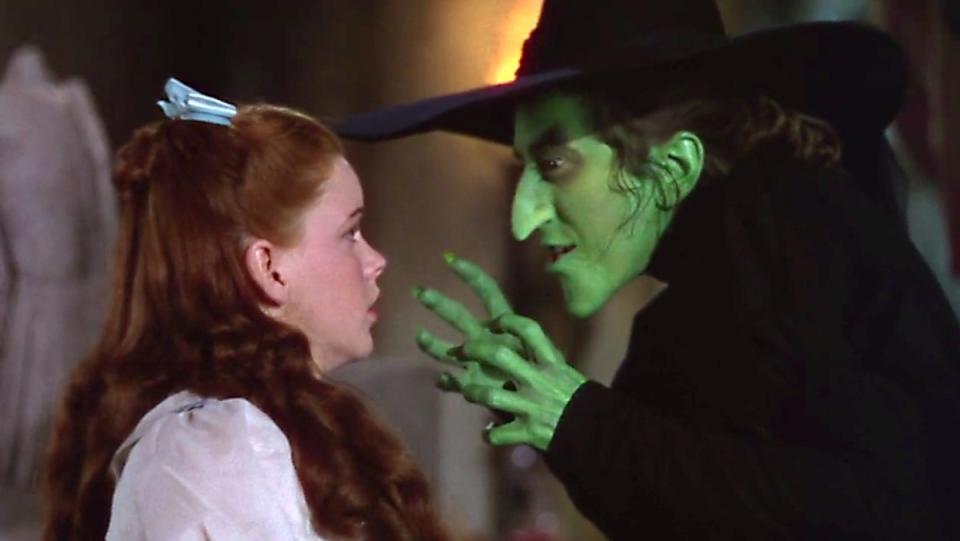 The Wicked Witch of the West raises her hands at Dorothy in a scene from The Wizard of Oz.