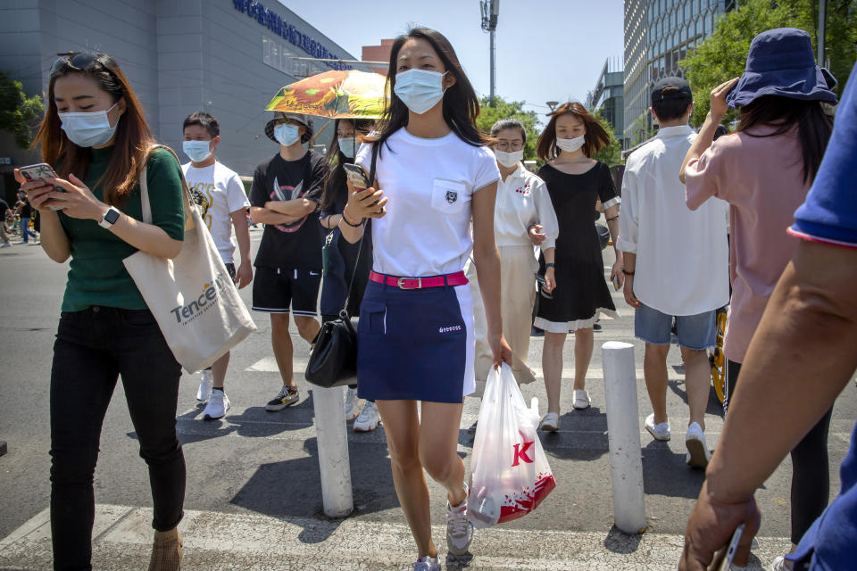 People wear face masks to protect against the coronavirus as they walk across an intersection in Beijing, Friday, June 5, 2020. China on Friday reported five new confirmed coronavirus cases, all of them brought by Chinese citizens from outside the country. (AP Photo/Mark Schiefelbein)