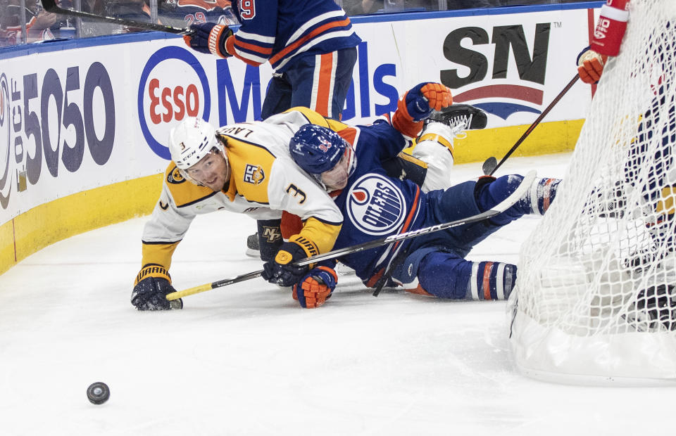 Nashville Predators' Jeremy Lauzon (3) and Edmonton Oilers' Ryan Nugent-Hopkins (93) battle for the puck during the second period of an NHL hockey game in Edmonton on Saturday Nov. 4, 2023. (Jason Franson/The Canadian Press via AP)