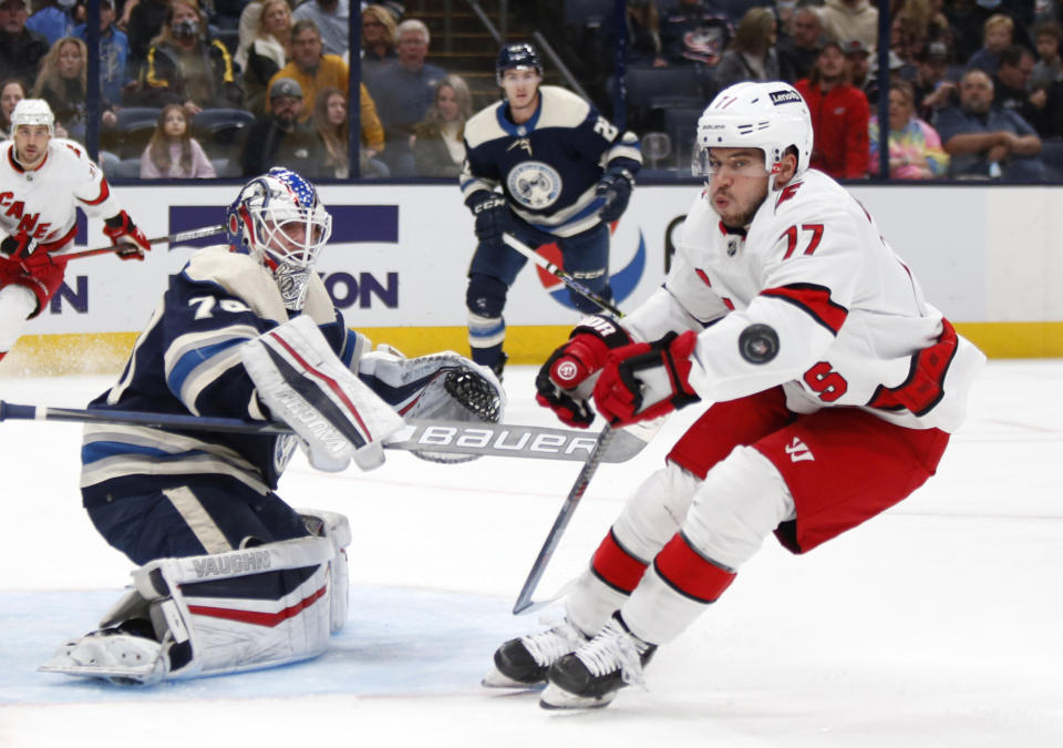 Columbus Blue Jackets goalie Joonas Korpisalo, left, stops a shot in front of Carolina Hurricanes defenseman Tony DeAngelo during the first period of an NHL hockey game in Columbus, Ohio, Saturday, Oct. 23, 2021. (AP Photo/Paul Vernon)