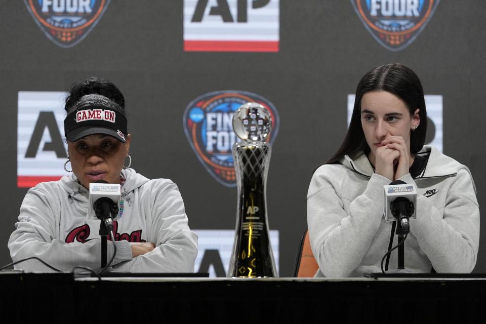 Iowa's Caitlin Clark listens as South Carolina head coach Dawn Staley speaks during a news conference announcing the AP NCAA Women's Coach and Player of the Year Thursday, April 4, 2024, in Cleveland. (AP Photo/Morry Gash)