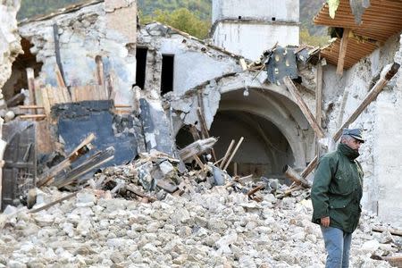 An officer of the State Forestry Corp national police stands in front of a collapsed church in Campi di Norcia, central Italy, October 27, 2016. REUTERS/Emiliano Grillotti