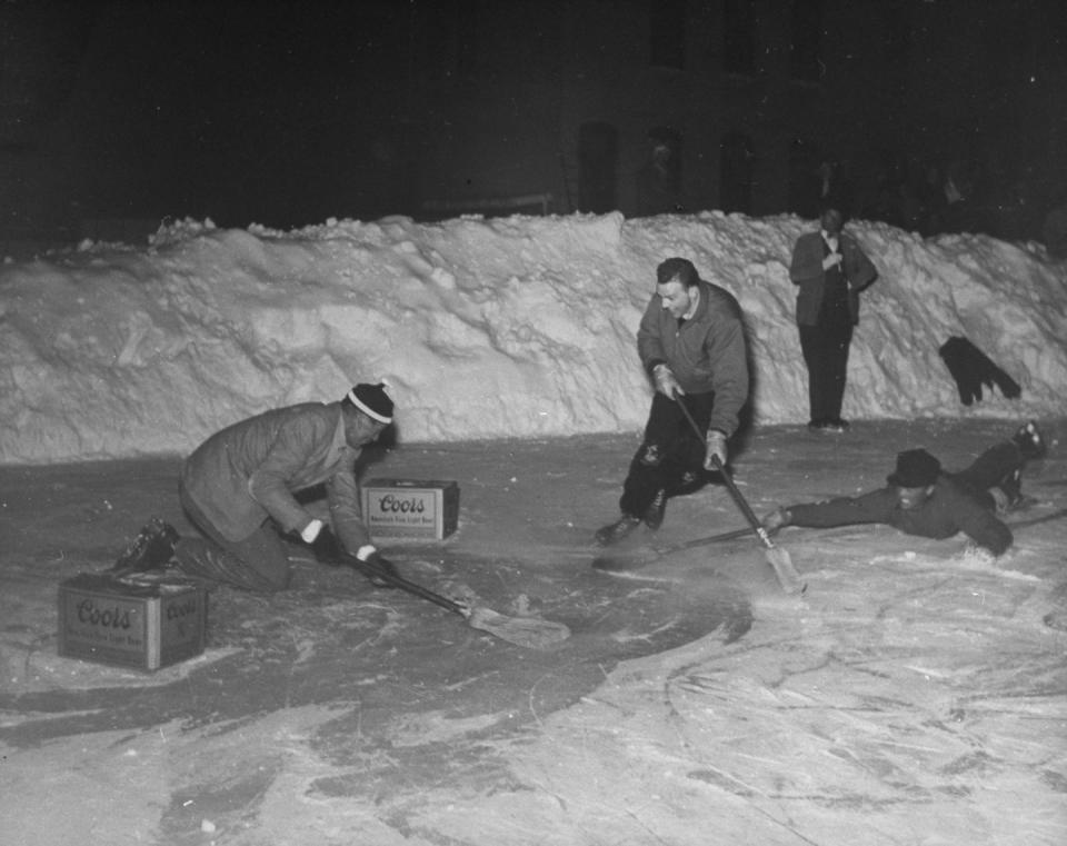 <p>While playing a game of pond hockey, Gary Cooper sneaks by his opponent and charges toward the goal. He was on a ski vacation circa 1949. </p>