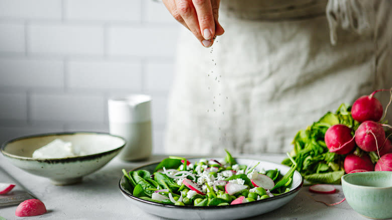 Chef sprinkling salt on salad