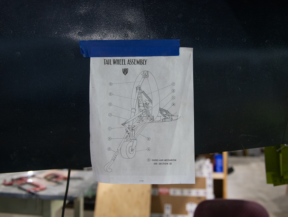 Volunteers from all backgrounds can take part in restoring or building an aircraft. A diagram of the tail wheel assembly is taped to the back of the aircraft.
