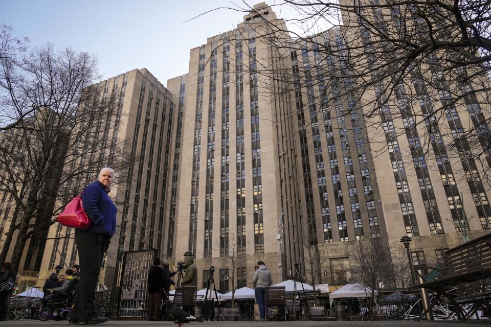 Pedestrians stand outside Manhattan Criminal Court as media and security amass nearby, Monday, April 3, 2023, in New York. Former President Donald Trump is expected to travel to New York to face charges related to hush money payments. Trump is facing multiple charges of falsifying business records, including at least one felony offense, in the indictment handed up by a Manhattan grand jury. (AP Photo/John Minchillo)