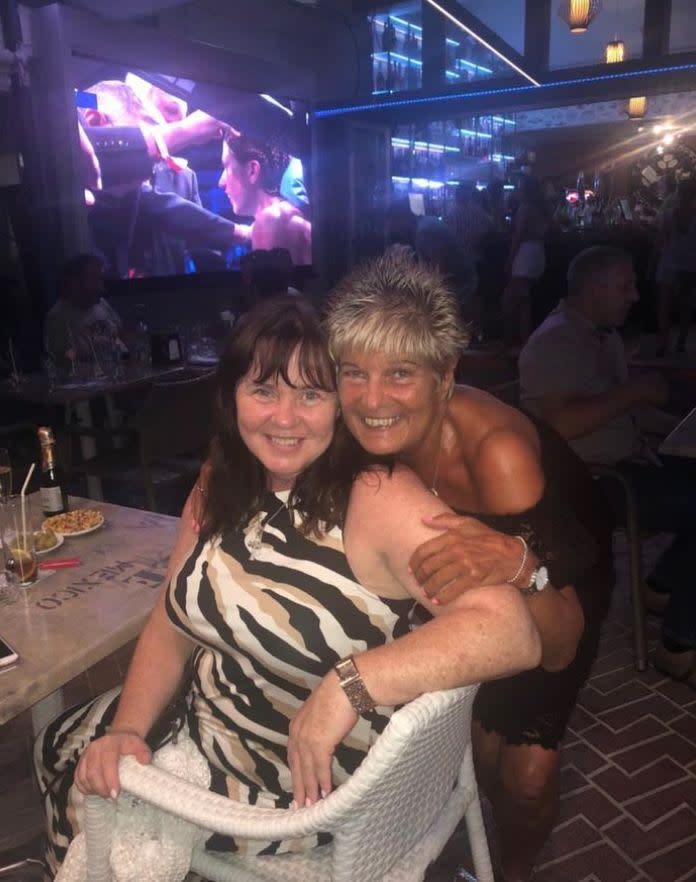 Coleen Nolan in zebra-print dress being hugged by a woman