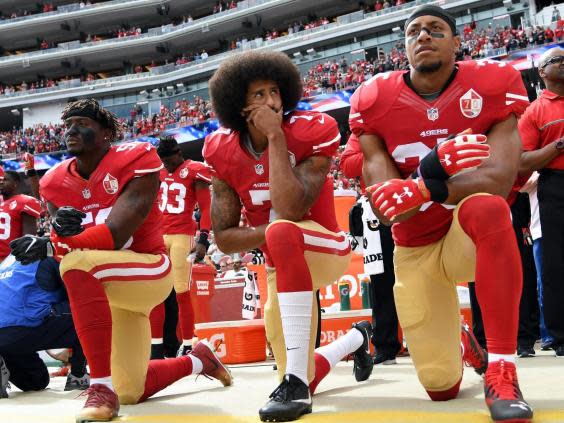 Eli Harold, Colin Kaepernick and Eric Reid of the San Francisco 49ers kneel on the sideline during the anthem (Getty)