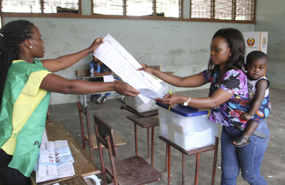 A woman carries a baby as she votes in Maputo, Mozambique, Tuesday, Oct. 15, 2019 in the country's presidential, parliamentary and provincial elections. Polling stations opened across the country with 13 million voters registered to cast ballots in elections seen as key to consolidating peace in the southern African nation. (AP Photo/Ferhat Momade)