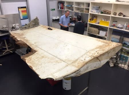 Australian and Malaysian officials examine aircraft debris at the Australian Transport Safety Bureau headquarters in Canberra, Australia, July 20, 2016 after it was found on Pemba Island, located near Tanzania, in late June and was transported to Australia for examination. Australian Transport Safety Bureau/Handout via REUTERS