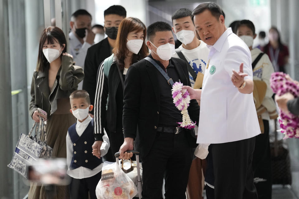 Thailand's Public Health Minister Anutin Charnvirakul, right, gives garland to Chinese tourists on their arrival at Suvarnabhumi International Airport in Samut Prakarn province, Thailand, Monday, Jan. 9, 2023. Thailand is looking forward to hosting large numbers of visitors from China again after Beijing eased travel restrictions on Sunday. Chinese were about one-third of the total number of tourists visiting Thailand before the coronavirus pandemic and the authorities hope they can help its lucrative tourism industry recover. (AP Photo/Sakchai Lalit)