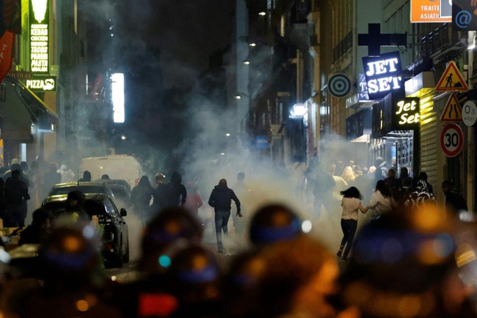 Demonstrators run as French police officers use tear gas in Paris (AFP via Getty Images)