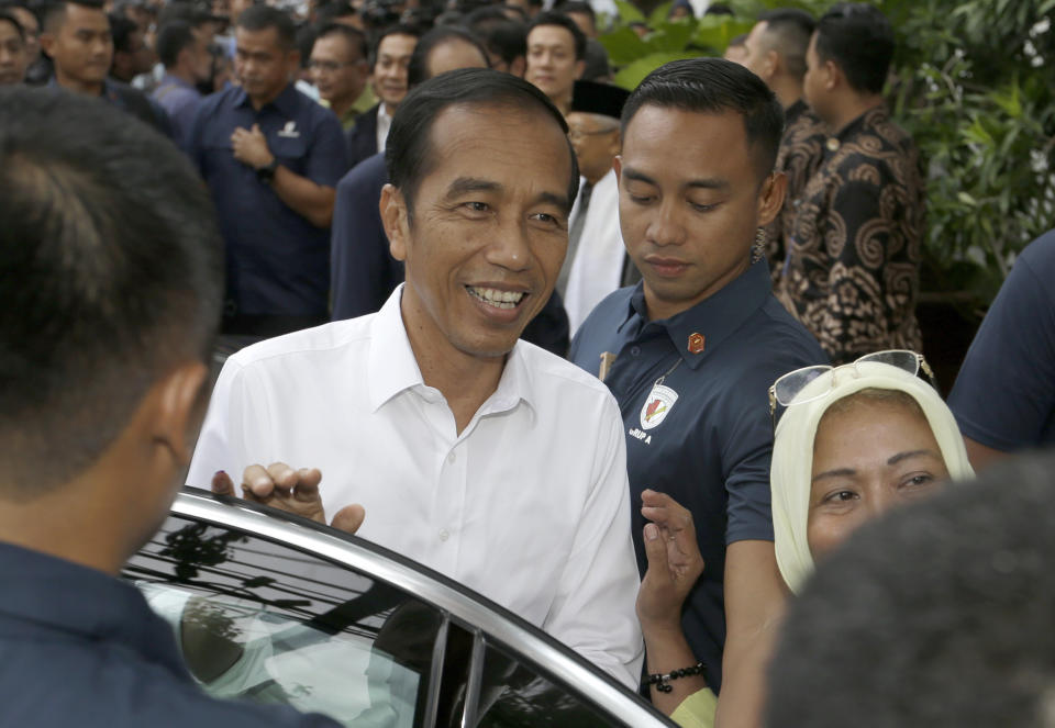 Incumbent Indonesian President Joko Widodo, center, pauses to be taken a photo by supporters as he leaves after a meeting with leaders of his coalition parties in Jakarta, Indonesia, Thursday, April 18, 2019. Widodo said Thursday he was won re-election after receiving an estimated 54% of the vote, backtracking on an earlier vow to wait for official results after his challenger made improbable claims of victory. (AP Photo/Achmad Ibrahim)