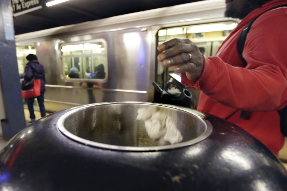 A subway passenger tosses trash in a Chambers Street platform receptacle, in New York, Thursday, March 30, 2017. Faced with the problem of too much litter and too many rats in their subway stations, New York City transit officials began an unusual social experiment a few years ago. They removed trash bins entirely from select stations, figuring it would deter people from bringing garbage into the subway in the first place. This week, they pulled the plug on the program after reluctantly concluding that it was a failure. (AP Photo/Richard Drew)