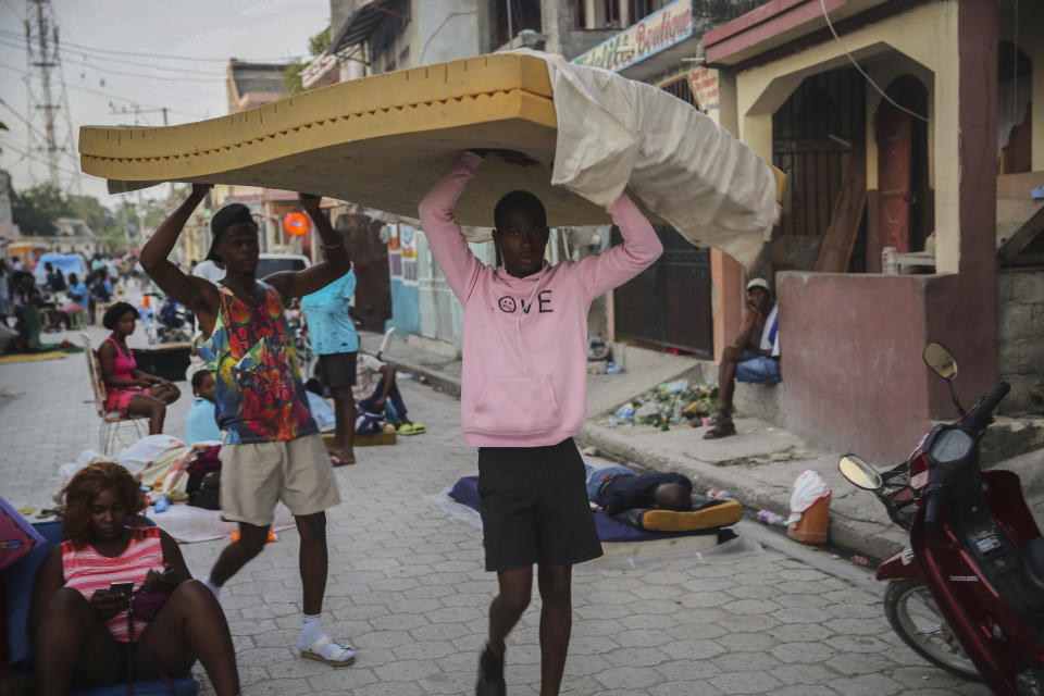 Men carry a mattress as people sleep on the streets after Saturday´s 7.2 magnitude earthquake in Les Cayes, Haiti, Sunday, Aug. 15, 2021. (AP Photo/Joseph Odelyn)