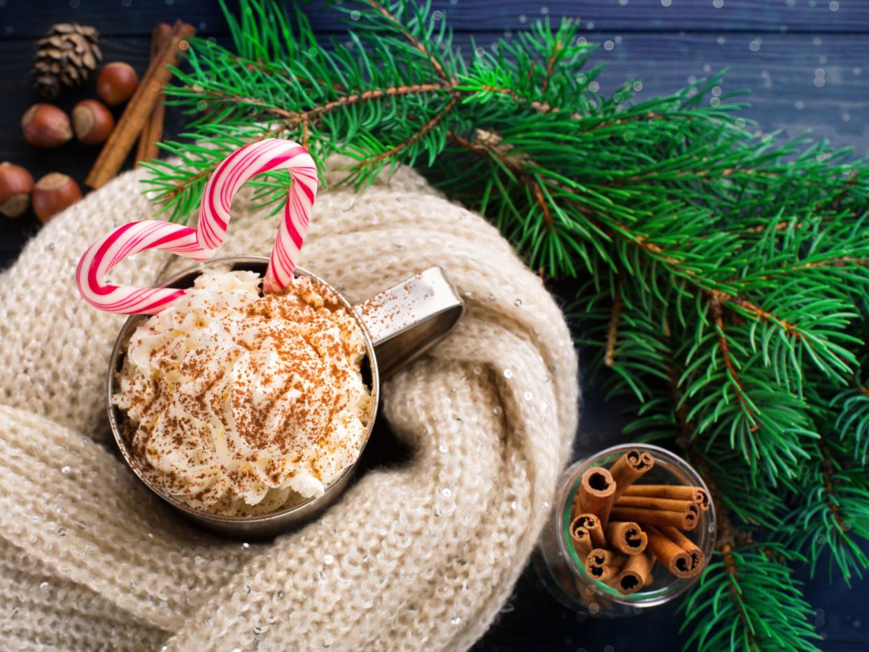 Christmas Homemade Peppermint Hot Chocolate with Whipped Cream and Candy Cane, top view. Winter time holiday snowfall concept, dark wooden background