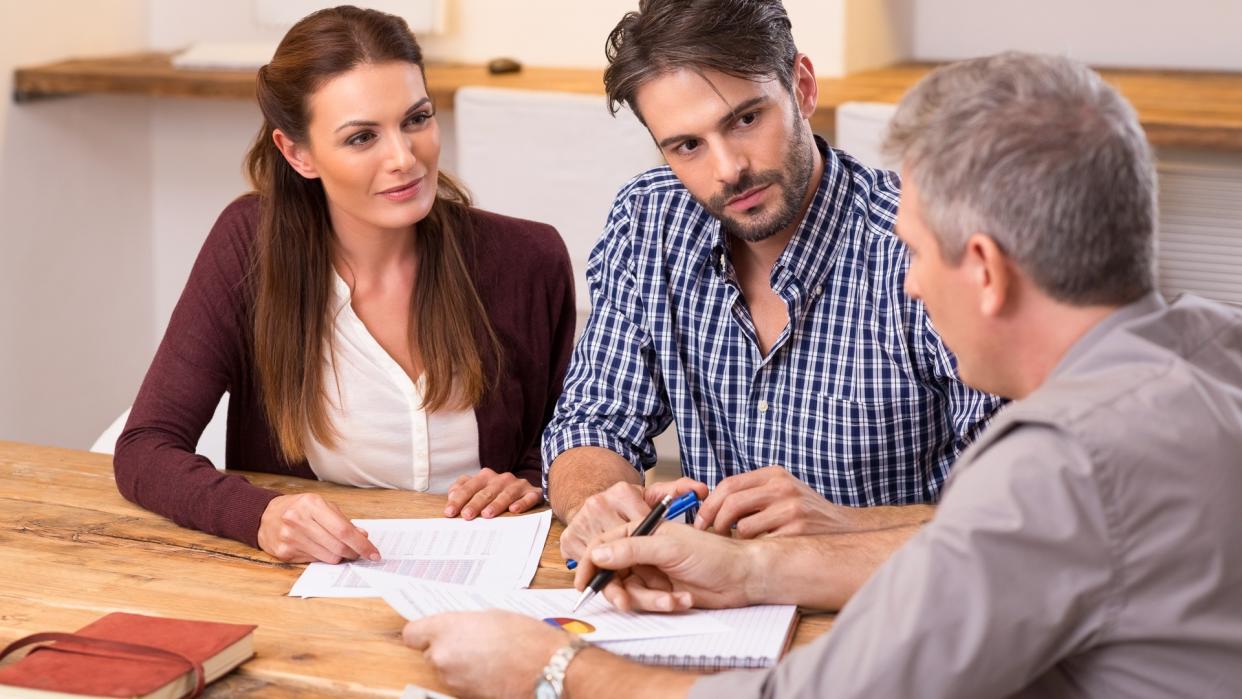 Businessman explaining loan policy to young couple.