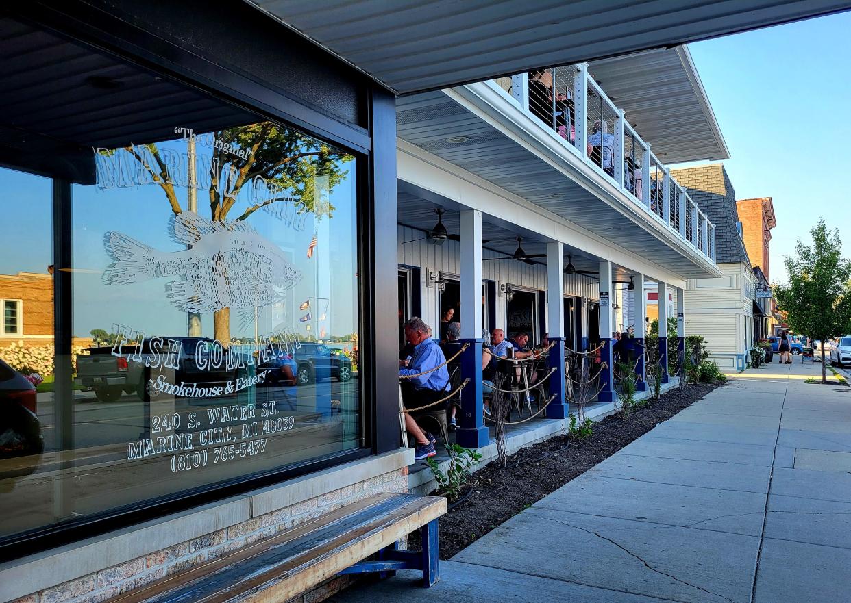 Diners enjoy the weather outside at Marine City Fish Company on Thursday, Aug. 10, 2023, in Marine City. It's one of several downtown establishments set to participate in the city's new social district, which allows residents and visitors to grab drinks to-go in specialty cups and venture for a walk downtown.