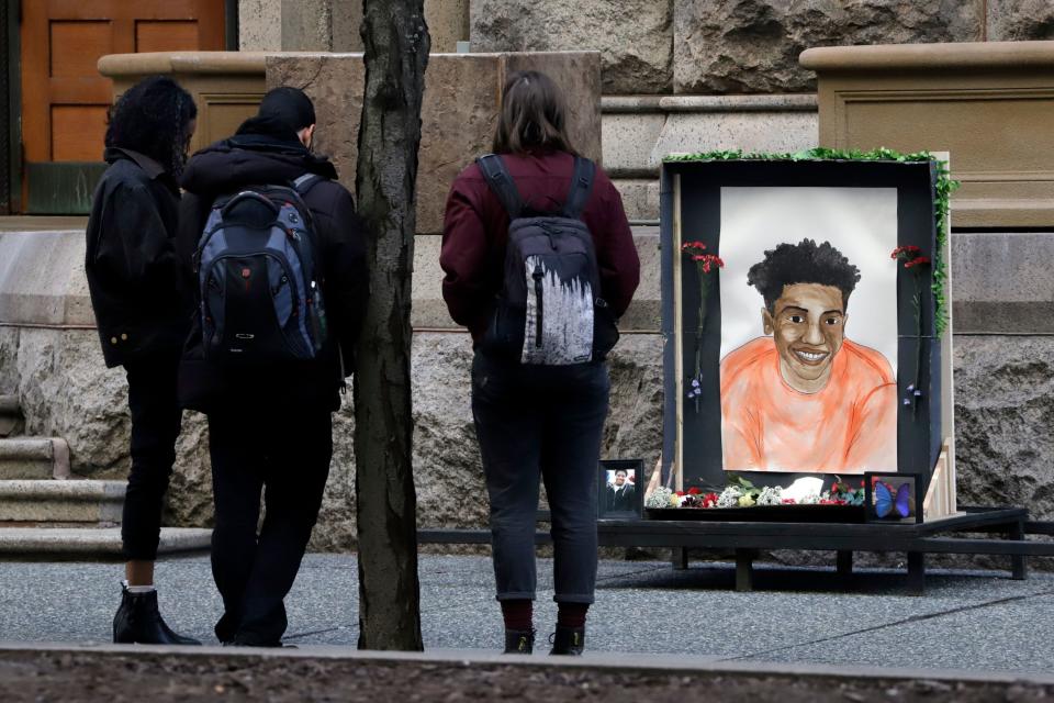 People gather around a memorial drawing of Antwon Rose II who was fatally shot as he fled during a traffic stop.