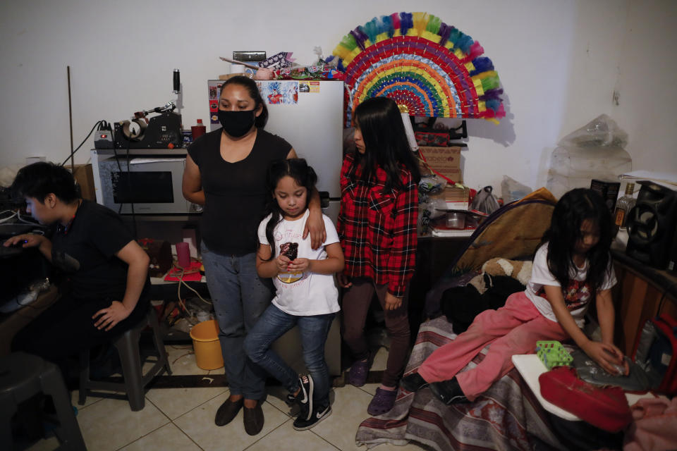 Blanca Evangelista Villada wears a mask amid her four daughters in the front room of their home in San Gregorio Atlapulco, Xochimilco, Mexico City, Wednesday, July 29, 2020. Only after a neighbor died of the coronavirus did Evangelista's in-laws begin to believe that the threat of COVID-19 was real. Soon, the older couple, their son and daughter-in-law, and two of their grandchildren were infected. Evangelista's in-laws, who lived with them, died in May. (AP Photo/Rebecca Blackwell)