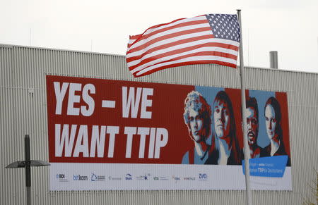 The flag of the USA flutters over a hall of the Hanover Fair decorated with a banner supporting the free trade agreement TTIP (Transatlantic Trade and Investment Partnership) in Hanover, Germany April 25, 2016. REUTERS/Wolfgang Rattay