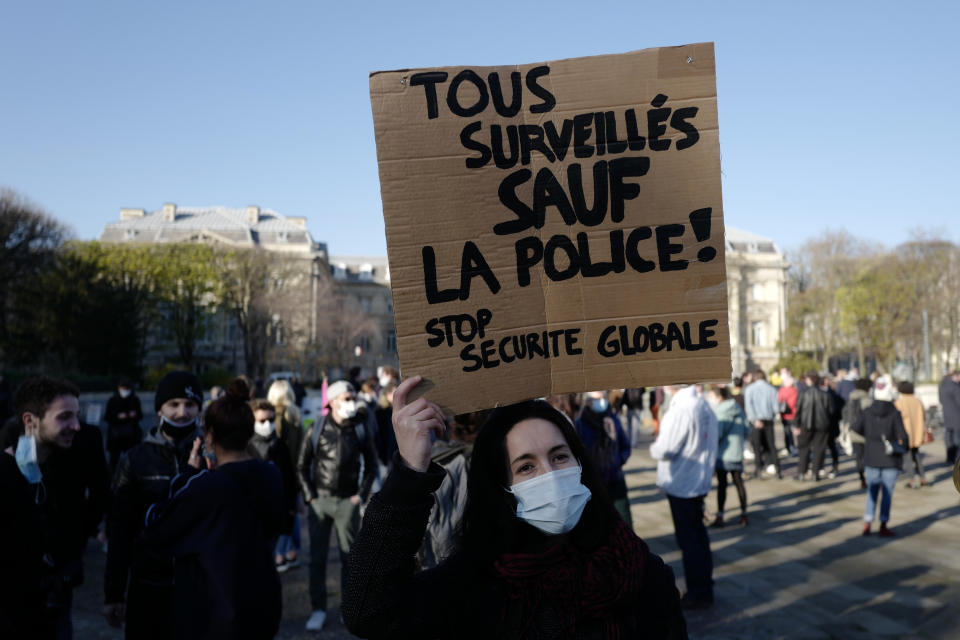 Demonstrator holds a poster reading " All monitored except the police, stop global security" during a demonstration Saturday, Nov. 28, 2020 in Lille, northern France. Critics of a proposed French security law in France that would restrict sharing images of police are gathering across the country in protest. Civil liberties groups and journalists are concerned that the measure will stymie press freedoms and allow police brutality to go undiscovered and unpunished. (AP Photo/Michel Spingler)