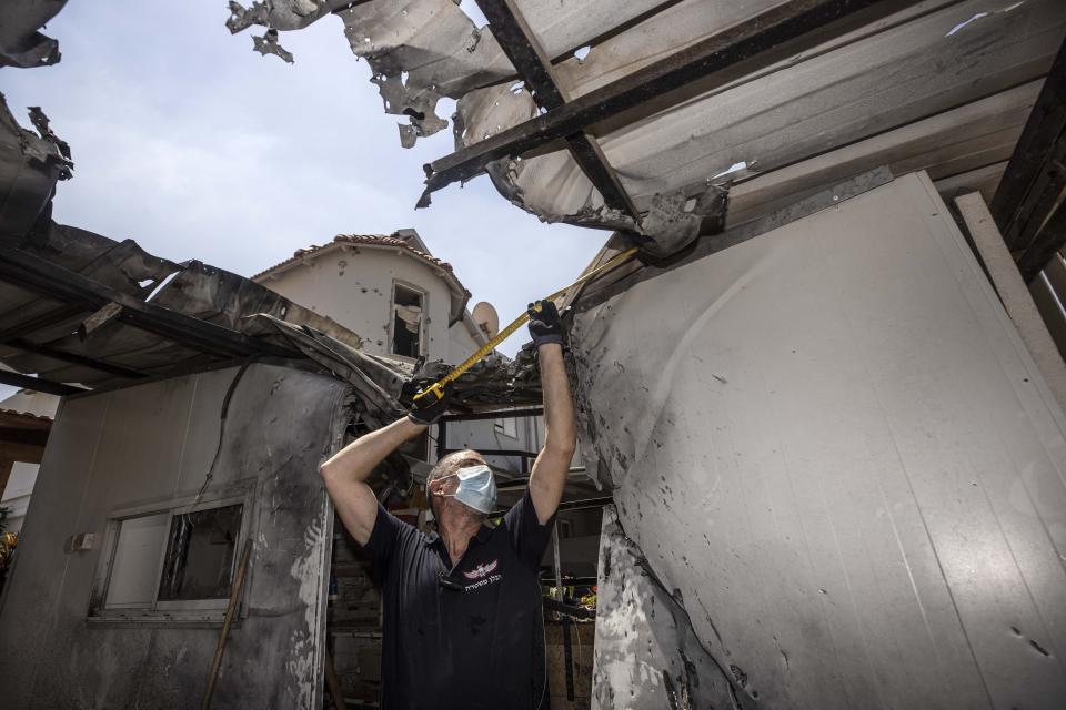 An Israeli police officer inspects the damage to a home after it was hit by a rocket fired by Palestinian militants from the Gaza Strip, in Sderot, Israel, Sunday, Aug. 16, 2020. (AP Photo/Tsafrir Abayov)