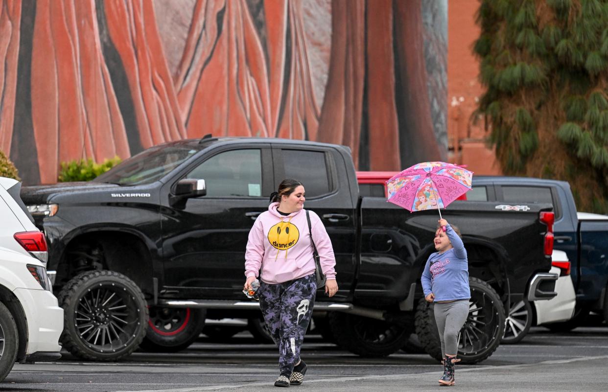 Lilah Florez, 6, catches up Amber Hinson of Visalia during Tuesday's brief rain in Downtown Visalia. 