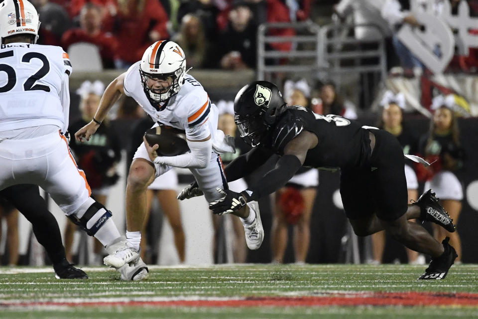 Virginia quarterback Anthony Colandrea, center, is hit by Louisville linebacker Antonio Watts, right, during the first half of an NCAA college football game in Louisville, Ky., Thursday, Nov. 9, 2023. (AP Photo/Timothy D. Easley)