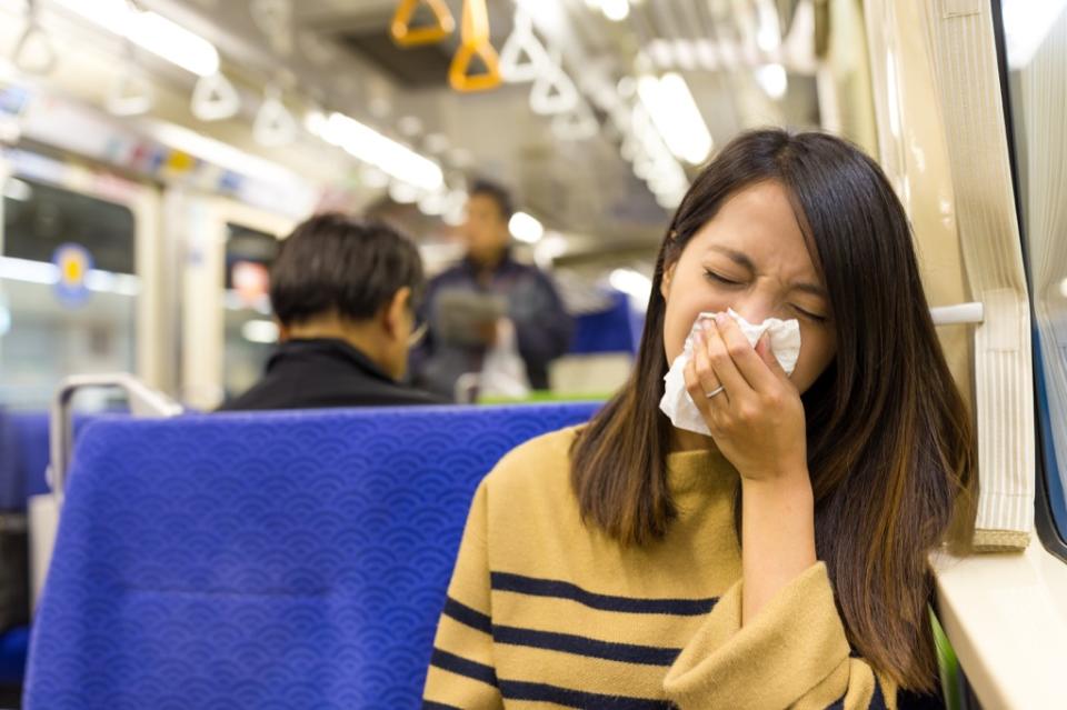 woman sick and sneezing on the bus
