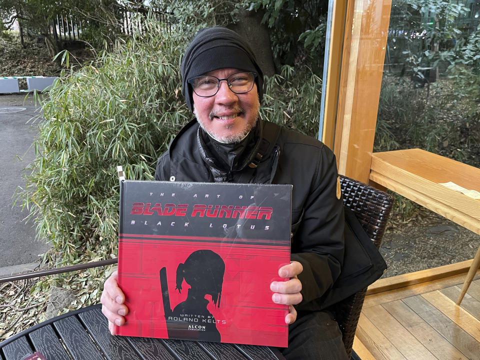 Japanese pop culture expert Roland Kelts holds a book about Blade Runner at Meiji Jingu in Tokyo on Feb. 25, 2023. Hit Japanese manga “One Piece” is coming to Netflix as a live-action series. Anime has a low production cost compared to live-action films, and computer-generated heroes don’t get sick or injured or make offensive remarks offscreen like real-life actors sometimes do, making it a marketable medium, said Kelts. (AP Photo/Yuri Kageyama)