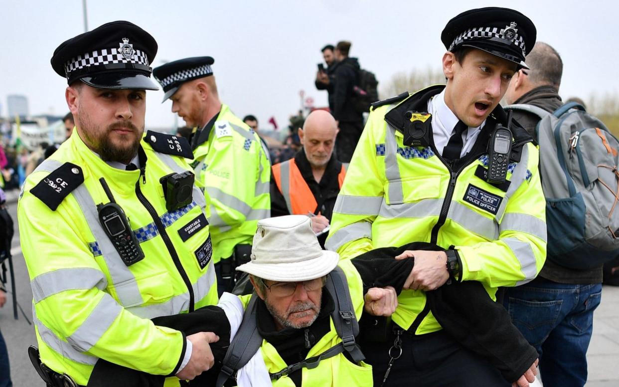 Police officers  carry an activist as they remove demonstrators from Waterloo Bridge - AFP