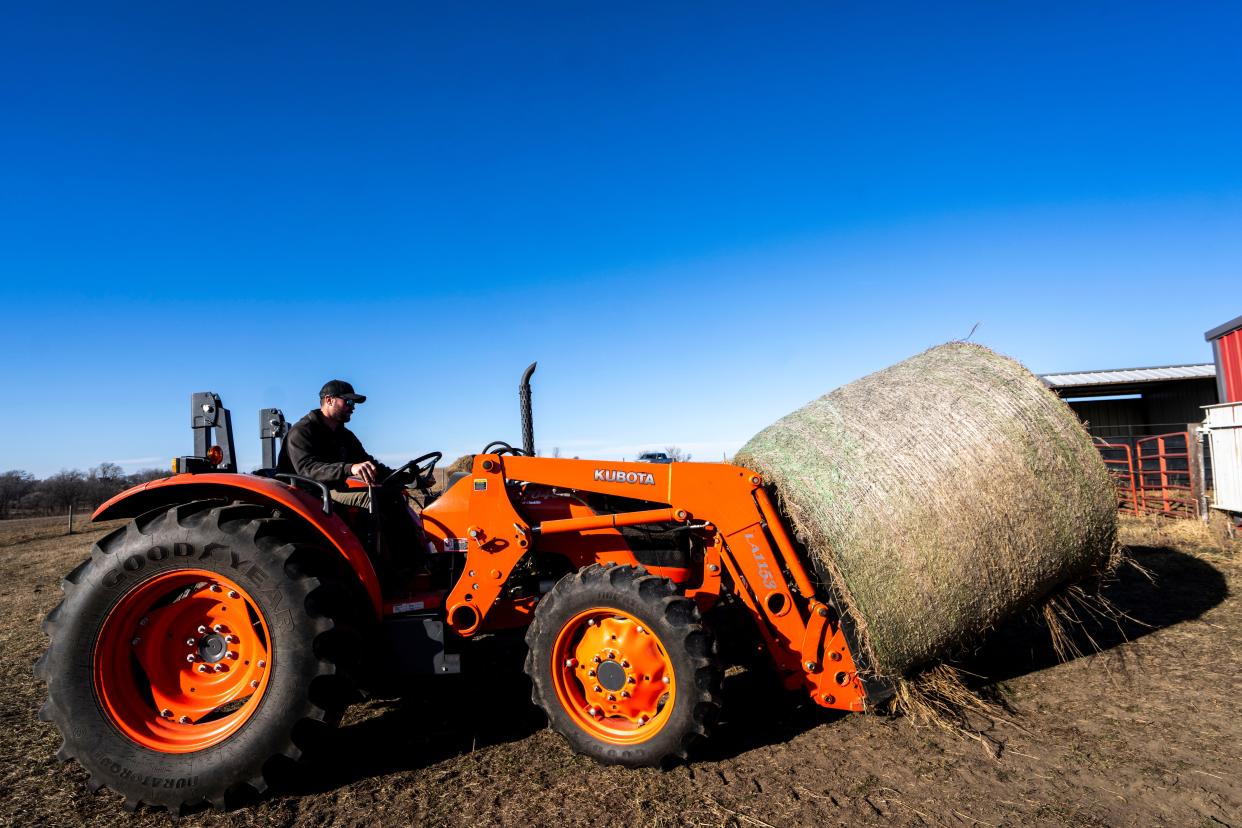 Farm manager Sam Applegate operates a tractor to move a hay bale at In Harmony farm on Nov. 30, 2023, in Earlham.