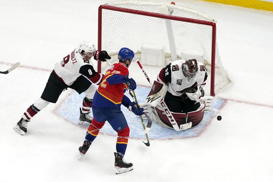 Arizona Coyotes goaltender Antti Raanta (32) deflects a puck as teammate Nick Schmaltz (8) and St. Louis Blues' Zach Michael Sanford (12) watch during the third period of an NHL hockey game Thursday, Feb. 4, 2021, in St. Louis. (AP Photo/Jeff Roberson)