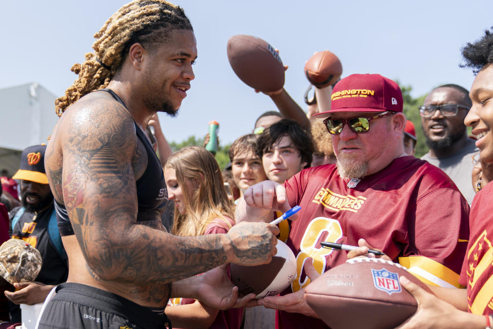 Washington Commanders defensive end Chase Young signs autographs for fans at the end of an NFL football practice at the team's training facility, Friday, July 28, 2023, in Ashburn, Va. (AP Photo/Stephanie Scarbrough)