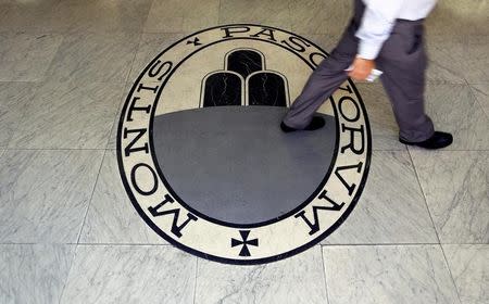 A man walks on a logo of the Monte Dei Paschi Di Siena bank in Rome, Italy September 24, 2013. REUTERS/Alessandro Bianchi/File Photo